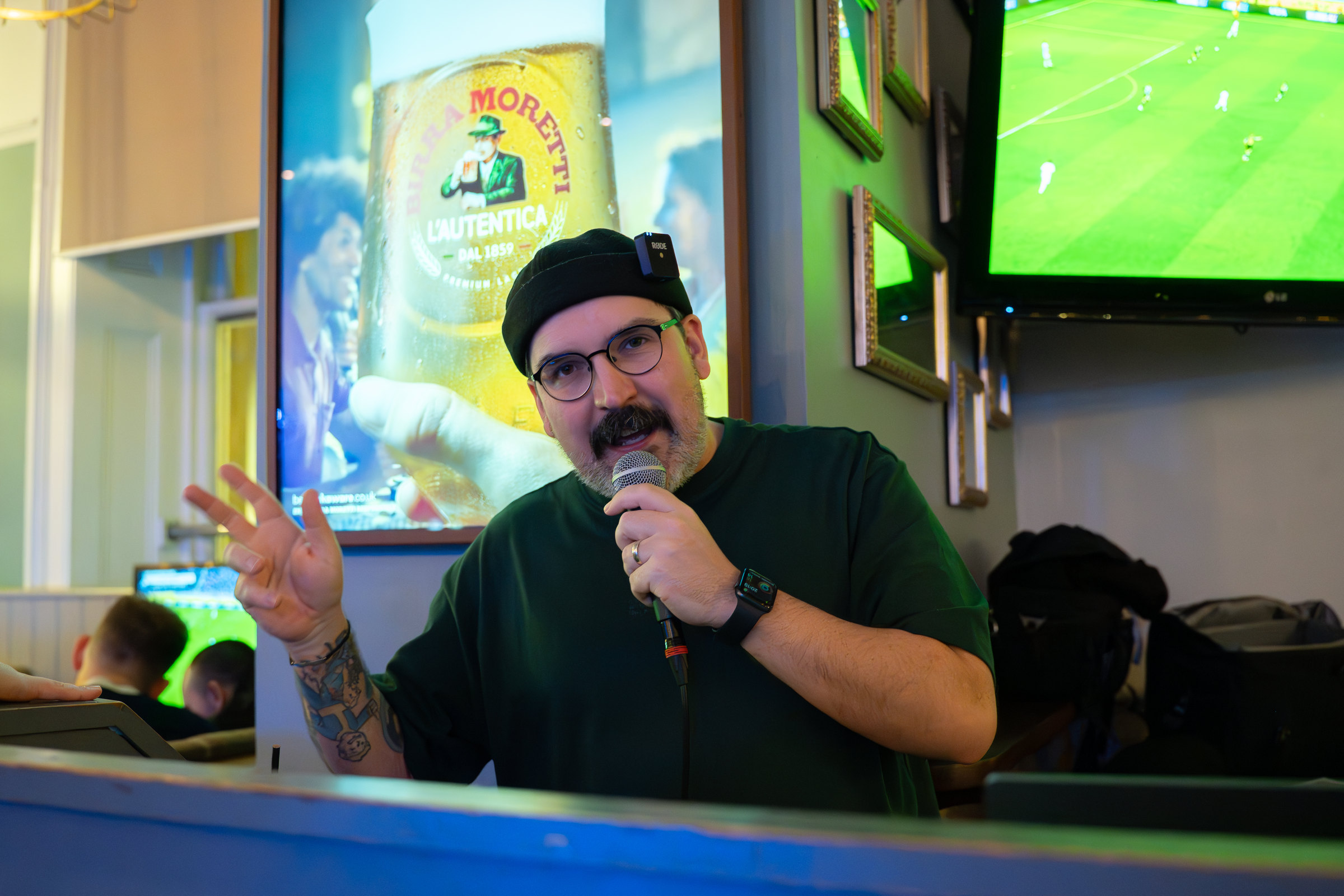 Gary hosting a quiz in a pub, microphone in hand, mid-question.